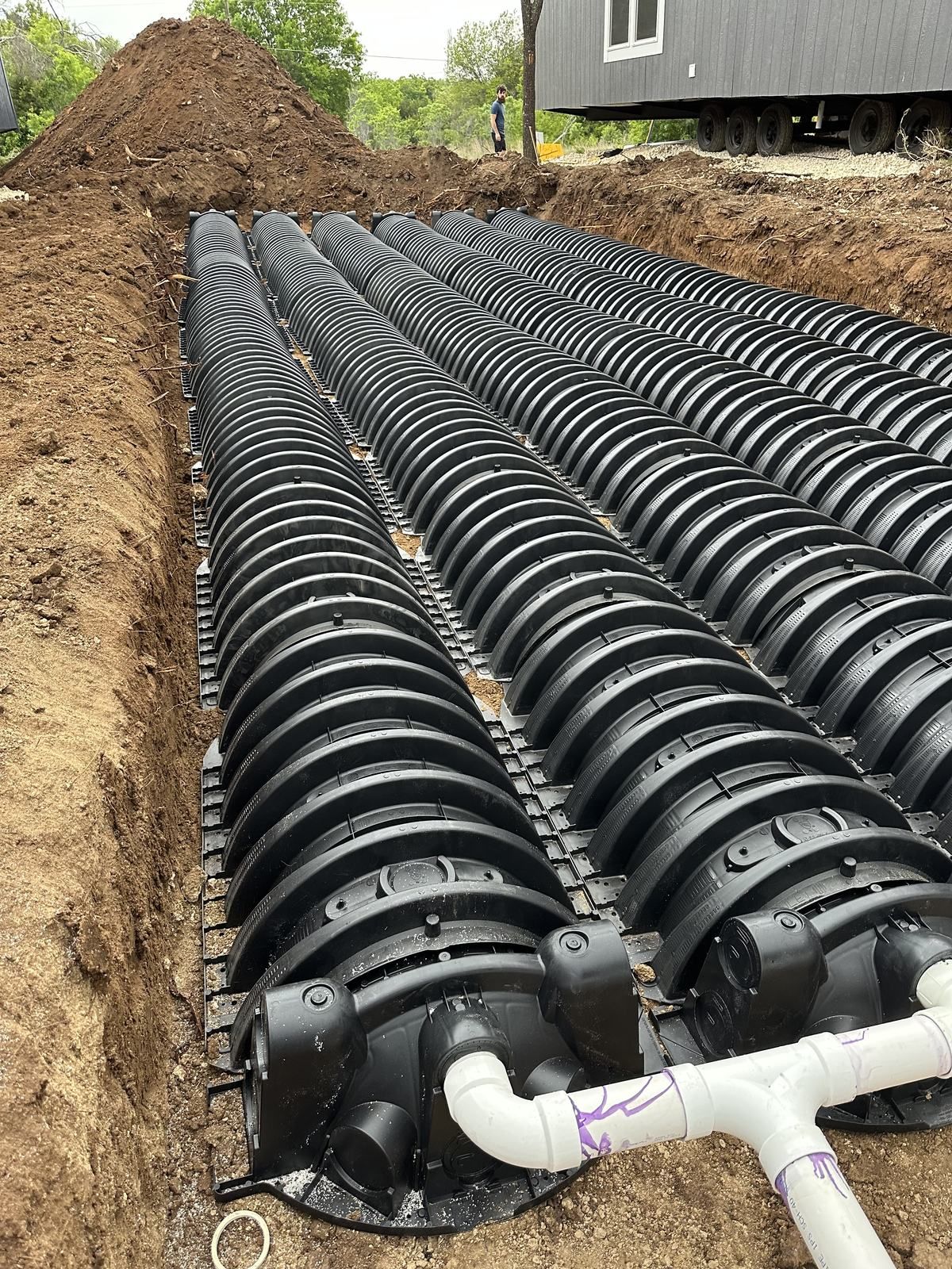 Rows of septic drain field chambers installed in an open excavation at a rural Texas home site