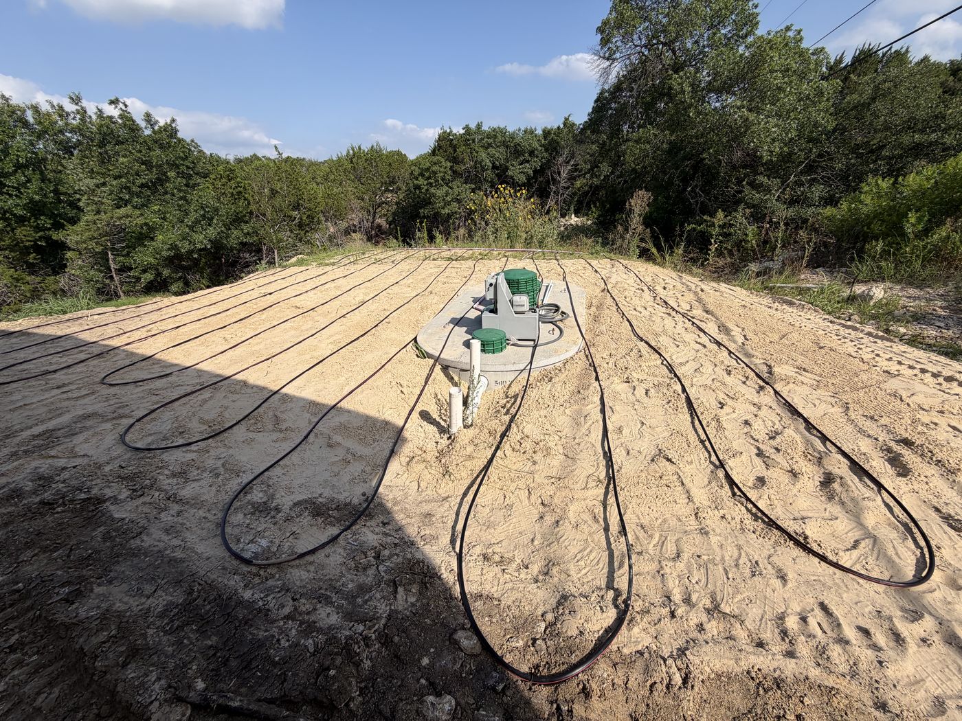 Completed aerobic septic system with drip tubing laid over a sand mound on a wooded Texas lot